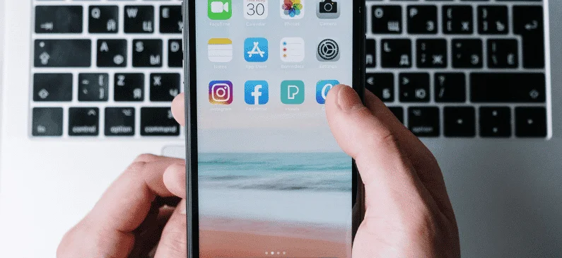 Revisando las aplicaciones de un iPhone al lado de un Mac